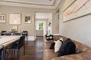 A spacious living area with a dining table, chairs, a leather sofa, and a large map on the wall. - Georgian Elegance in Islington, by Veeve (London)