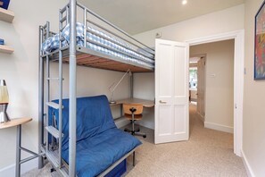 Habitación pequeña con literas, un escritorio, una silla y una lámpara.