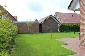 A residential area with brick houses, a well-maintained lawn, and a paved pathway. - Holiday home with 2 bedrooms (Greetsiel)