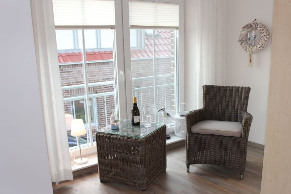 A balcony with wicker furniture, a bottle of wine, and a bird figurine.