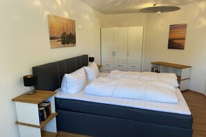 A bedroom with a bed, bedside tables, a wardrobe, and artwork on the walls. - Holiday apartment with 2 bedrooms (Hooksiel)