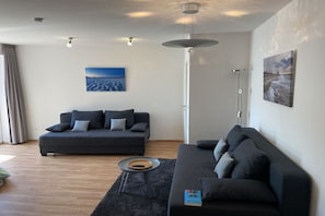 A modern living room with two dark sofas, a coffee table, and artwork on the walls. - Holiday apartment with 2 bedrooms (Hooksiel)