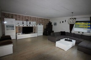 Ein modernes Wohnzimmer mit Flachbildfernseher, Kamin, Sofa und Couchtisch.