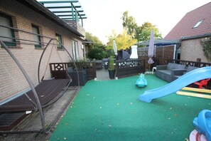 Ein Garten mit Schaukel, Rutsche und einem Spielbereich mit grüner Rasenfläche.