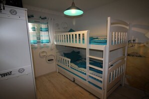 Ein Etagenbett für Kinder in Blau und Weiß, ein weißer Kleiderschrank und eine Pendelleuchte.