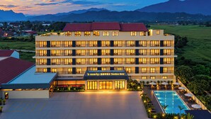 A multi-story hotel with a swimming pool and a view of the mountains. - Vangvieng THAVIKUN HOTEL (Vang Vieng)