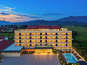 Un hotel a più piani con piscina e vista sulle montagne.