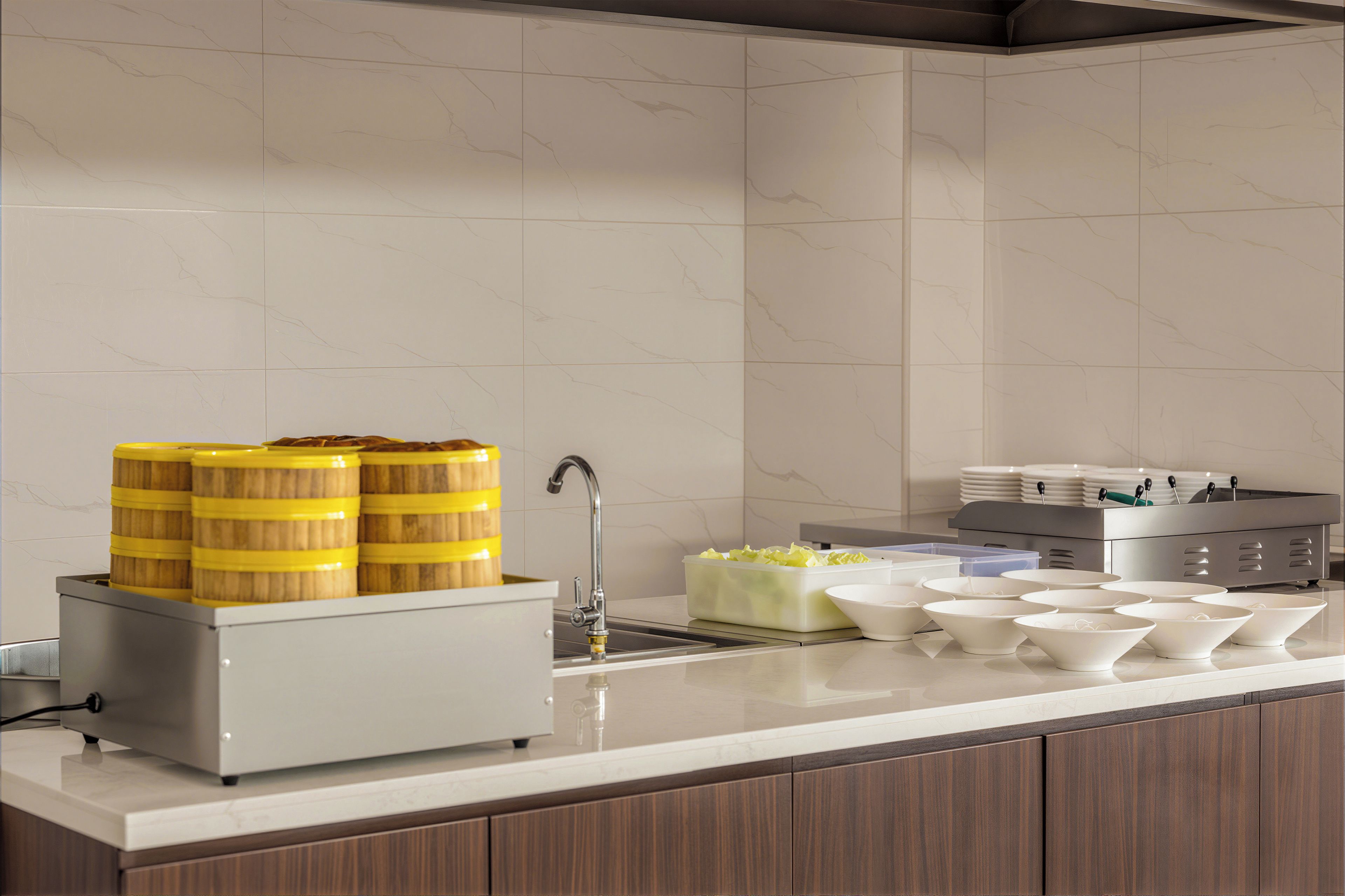 A kitchen with a sink, a food dispenser, and various bowls and containers.