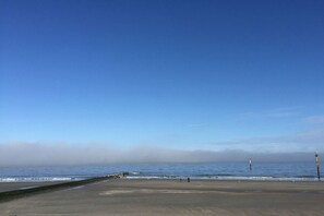 Ein Strand mit blauem Himmel, ruhiger See und einigen Spaziergängern.