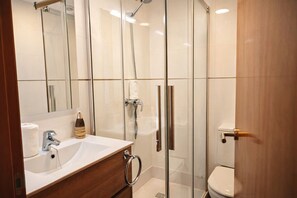 A modern bathroom with a glass-enclosed shower, a wooden vanity with a sink, and a toilet. - Mountain Valley Lodging (Molló)