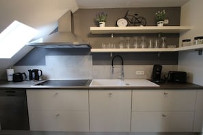 A modern kitchen with a built-in dishwasher, a sink, and a countertop with a coffee maker. - Holiday apartment with 1 bedroom (Rhauderfehn)