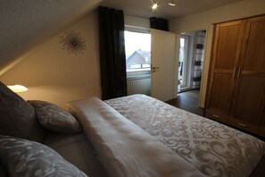 Une chambre à coucher avec un lit, une armoire et une vue sur l’extérieur, visible à travers une porte ouverte.