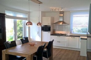 Eine moderne Küche mit weißen Schränken, einem Holztisch und Pendelleuchten.