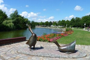 Un parc avec un étang, deux sculptures d’animaux en bronze et un parterre de fleurs.