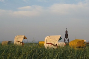 A grassy field with two wicker chairs and a yellow object in the background. - 120 Kurpark Residenz Cuxhaven (Cuxhaven)