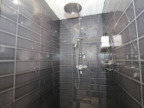 A shower area with a handheld showerhead, a wall-mounted faucet, and a towel rack. - The Annex at The Lodge (Shrewsbury)