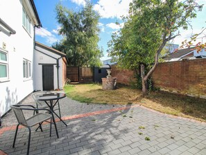 A patio area with a brick floor, a table with chairs, and a brick wall. - The Annex at The Lodge (Shrewsbury)