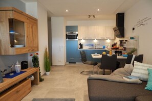 A compact living space with a kitchenette, a dining area, and a seating area with a sofa and chairs. - Holiday apartment with 1 bedroom (Dangast)