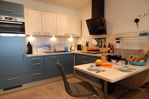 Una cocina moderna con armarios azules, horno empotrado, microondas y cafetera.