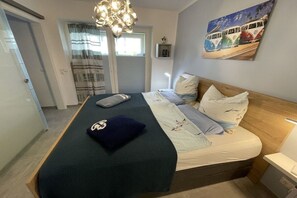 A bedroom with a bed, a bedside table, a wall-mounted painting, and a door. - Holiday apartment with 1 bedroom (Dangast)