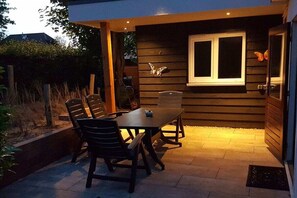 An outdoor patio with a table and chairs, a window with a butterfly decoration, and a door. - Small Horizon 101 Renesse (Renesse)