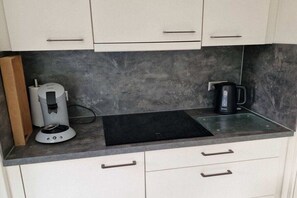 A kitchen with a coffee maker, a kettle, and a black countertop. - Small Horizon 101 Renesse (Renesse)