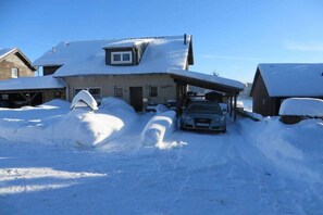 Ein Haus mit parkendem Auto davor, umgeben von Schnee.