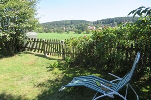 Ein Garten mit Holzzaun, Rasenfläche und einem Stuhl.