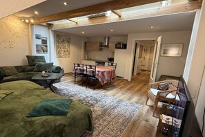 Ein gemütlicher Wohnbereich mit einer Couch, einem Esstisch mit Stühlen und einer Küche im Hintergrund.