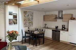 Eine moderne Küche mit Holzschränken, einem Esstisch mit Stühlen und einer Kaffeemaschine.