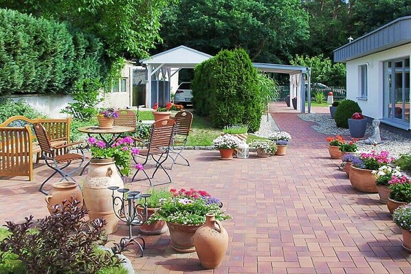 A patio area with outdoor seating, potted plants, and a covered structure. - Holiday home in Waren with swimming pool (Waren)