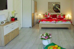 A hotel room with a bed, bedside lamps, a TV, a desk with a lamp, a vase with flowers, and a fruit bowl. - Holiday home in Waren with swimming pool (Waren)