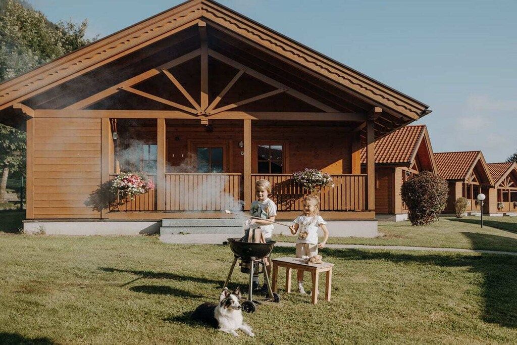 Eine Holzhütte mit Veranda, Grill und Hund.