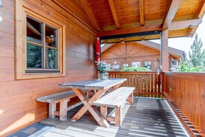 A wooden deck with a picnic table and benches, a covered area with a wooden ceiling, and a view of a mountain in the background. - Cabin in Maishofen with swimming pool (Maishofen)