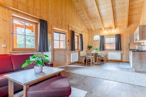 A wooden interior with a sofa, dining table, and kitchen area. - Cabin in Maishofen with swimming pool (Maishofen)