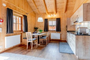 A wooden interior with a dining table, chairs, a kitchen area, and a radiator. - Cabin in Maishofen with swimming pool (Maishofen)