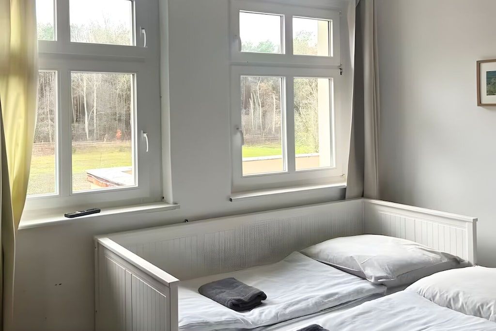 Une chambre avec deux lits, une fenêtre et un radiateur.