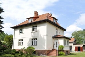 Ein zweistöckiges Gebäude mit flachem Dach, zahlreichen Fenstern und einem Backsteinfundament.