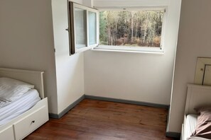 A bedroom with a single bed, a window, and a radiator.