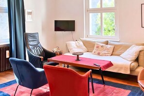 A living room with a sofa, a table, and a television.