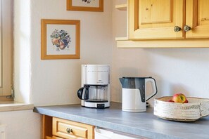 Eine Küche mit Kaffeemaschine, Wasserkocher und Obstschale auf der Arbeitsfläche.