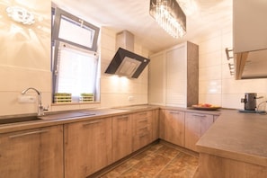 A modern kitchen with wooden cabinets, a built-in oven, and a window with blinds. - Holiday apartment in Pirna with swimming pool (Pirna)