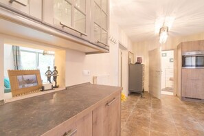 A kitchen with a marble countertop, wooden cabinets, a built-in oven, and a chandelier. - Holiday apartment in Pirna with swimming pool (Pirna)