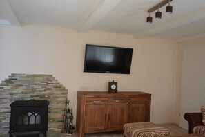 Ein Wohnzimmer mit Kamin aus Stein, einem Holzkabinett und einem flachbildfernseher an der Wand.
