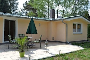 Ein Haus mit einer Terrasse, Gartenmöbeln und einem Blumentopf.