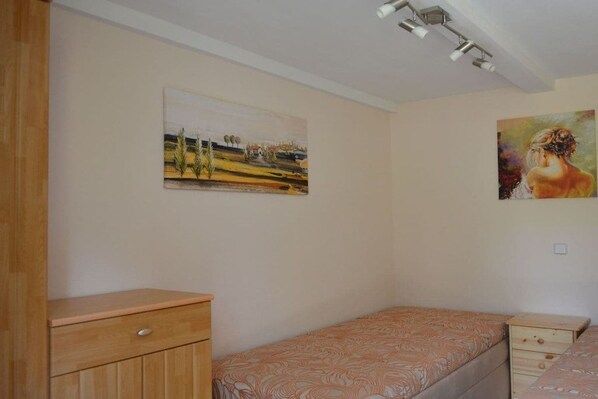 Ein Schlafzimmer mit einem Einzelbett, einer Holzkommode und zwei Bildern an der Wand.