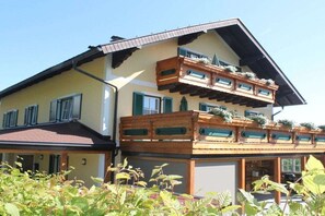 Ein zweistöckiges Gebäude mit einem Balkon im oberen Geschoss, einer überdachten Veranda und einer Garage.