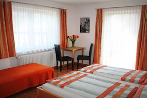 Ein Hotelzimmer mit zwei Betten, einem Tisch mit Stühlen und einem Fenster mit Vorhängen.