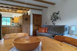 Ein gemütliches Wohnzimmer mit einem Holzesstisch, einem grauen Sofa und einer Wanddekoration.