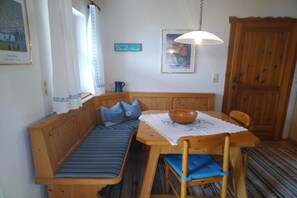 A wooden bench with cushions, a table with a bowl, and a wooden door. - Holiday home with 1 bedroom (Unterach am Attersee)